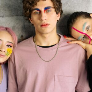 man in pink shirt with red and blue eyebrow make up